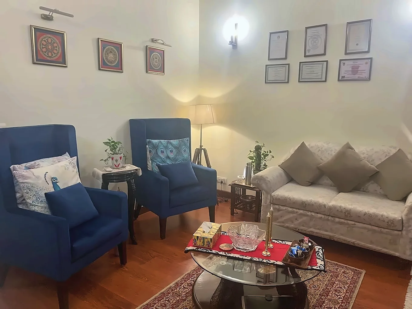 A quiet consultation room with two blue armchairs, a sofa and framed pictures