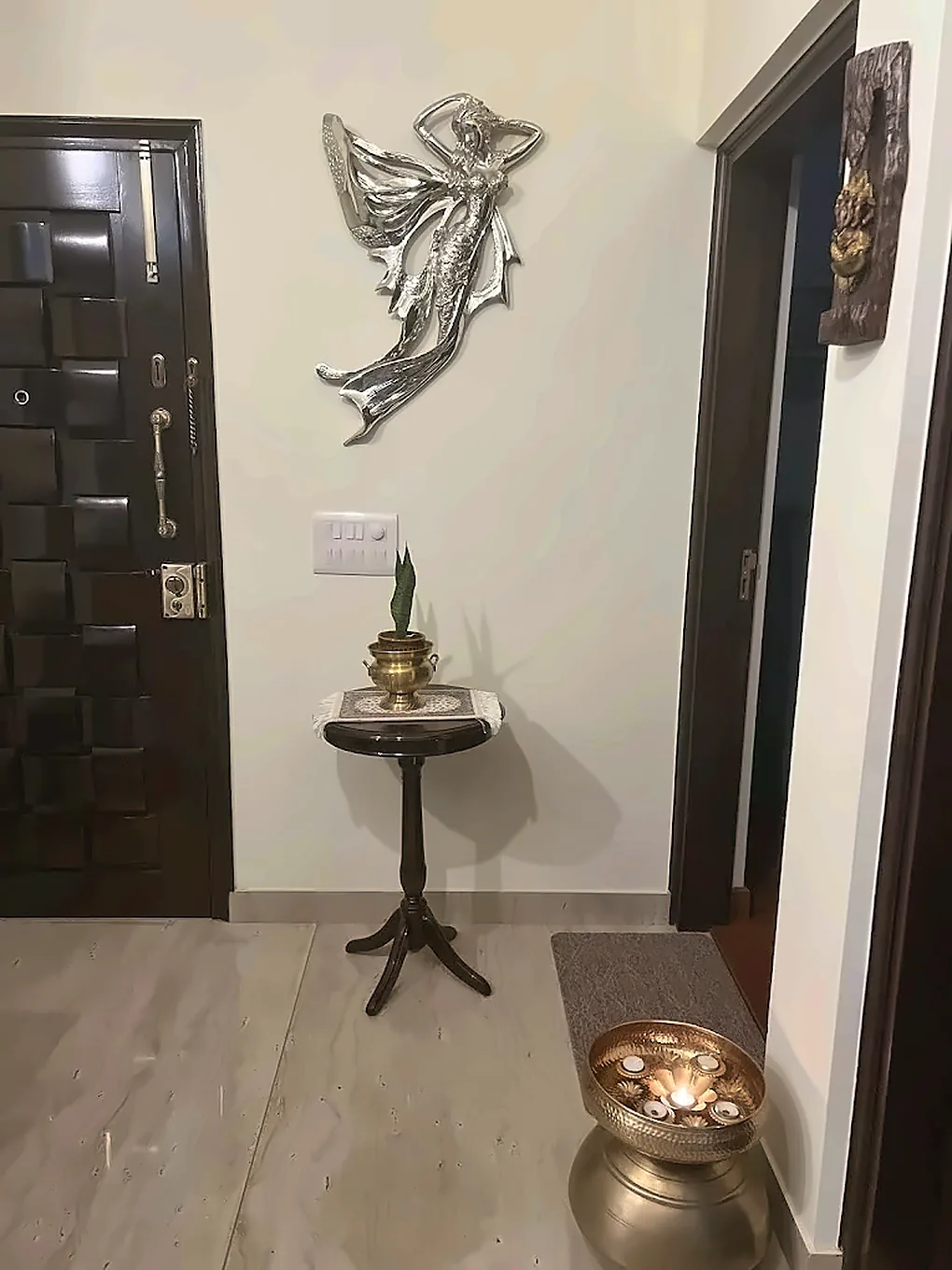 The entrance hallway, with a wall sculpture and a small brass lamp